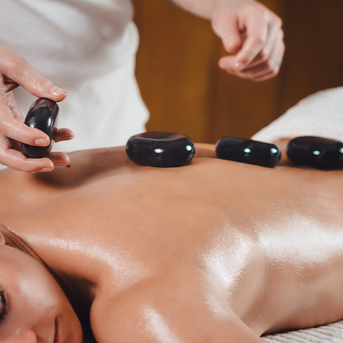 An individual receiving a soothing Hot Stone Massage at Majestic Medical Touch Spa, with warm stones placed along the body for deep relaxation.